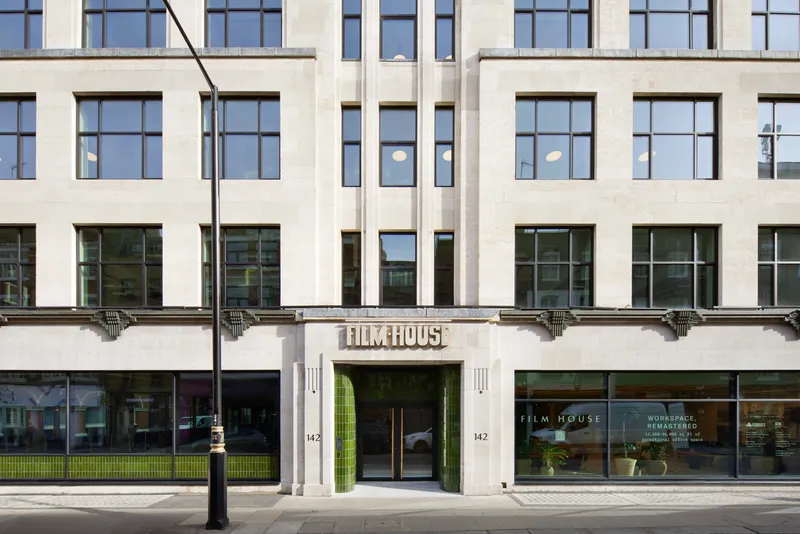 Art Deco stone office façade with green-tiled arched entrance and metal-framed windows